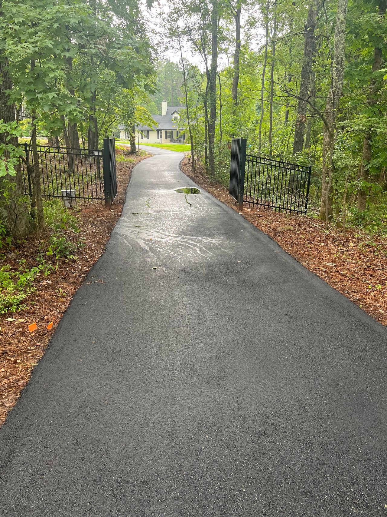 New asphalt driveway through a gate